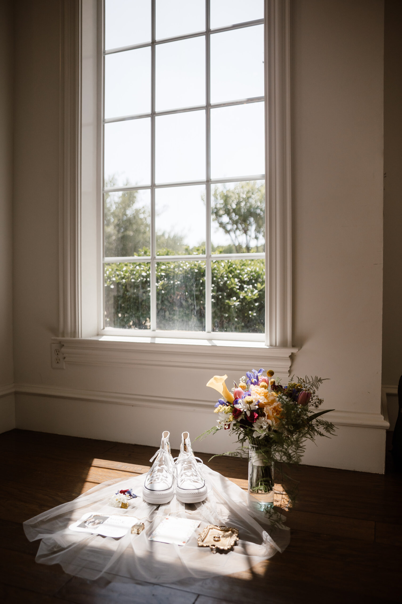 a beautiful picture of the brides shoes, veil and accessories sit in the sun beaming in through a window at the milestone mansion in denton, texas. artfully captured by shelly voss