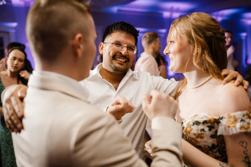 bride and groom share smiles with a guest at their wedding reception at the milestone mansion in denton, texas captured by wedding photographer shelly voss