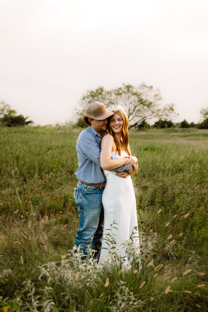 a couple standing in a field during blue hour while Shelly Voss photography captures their session