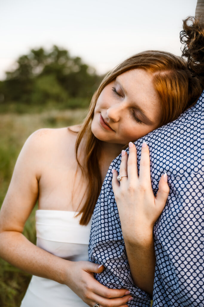fiance leans on her boyfriend during her engagement session showcasing her ring during blue hour photo session captured by shelly voss photography.