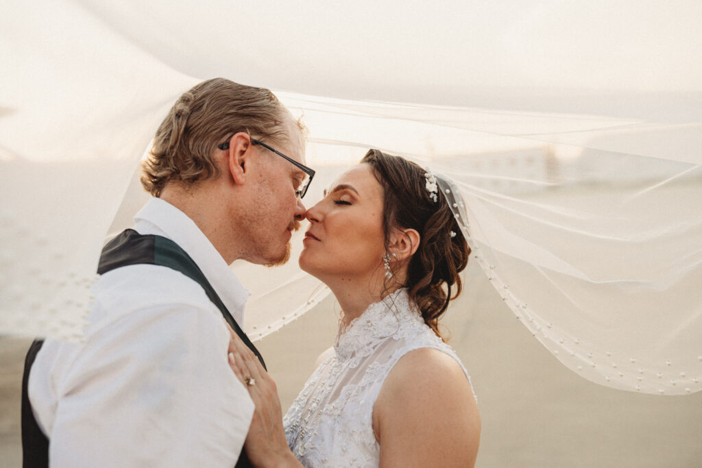 A bride and groom share a kiss under the brides veil during golden hour portraits captured by Mckinney wedding photographer Shelly Voss.