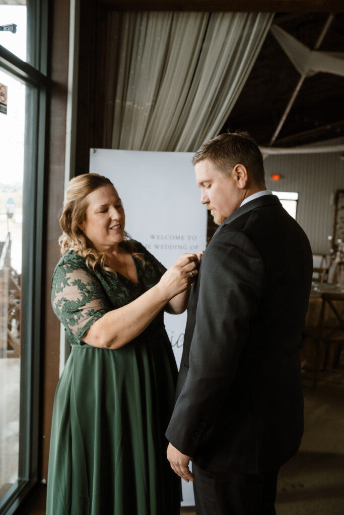 The mother of the groom pins a rose to his tuxedo as Shelly Voss captures the photo
