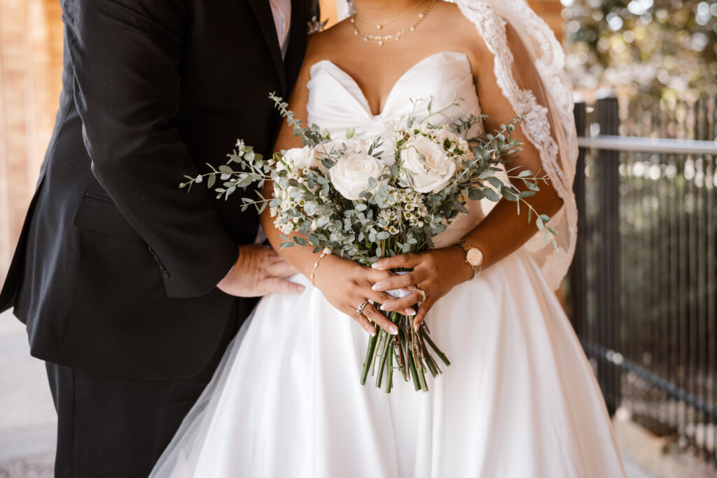 a close up photo of the brides bouquet as she holds it at her naval while Shelly Voss captures the moment
