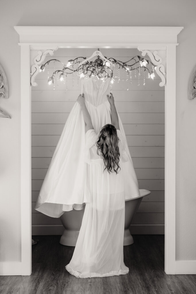Bride reaching for wedding dress in Chandelier Farm bridal suite
