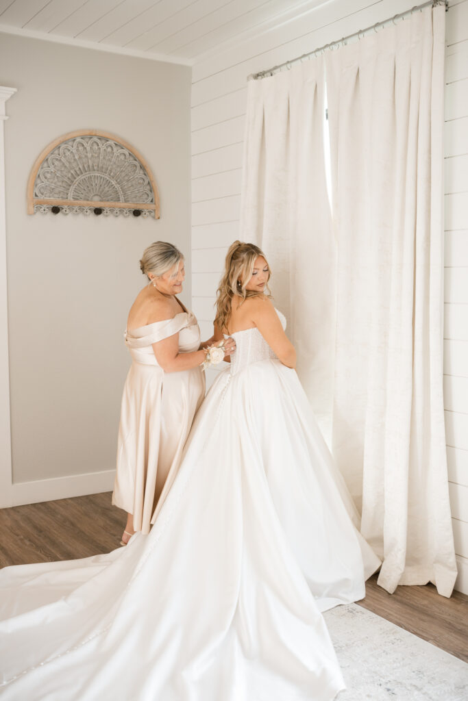 Bridesmaids helping bride with dress at Chandelier Farm Terrell Texas