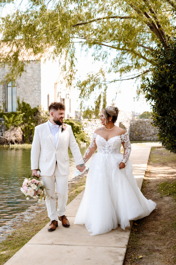 Wedding couple walking hand in hand along Adriatica waterfront near Bella Donna Chapel in McKinney Texas