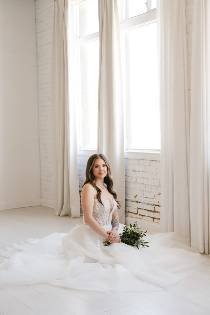 bride kneels on floor under her gown during her bridal session with shelly voss photography