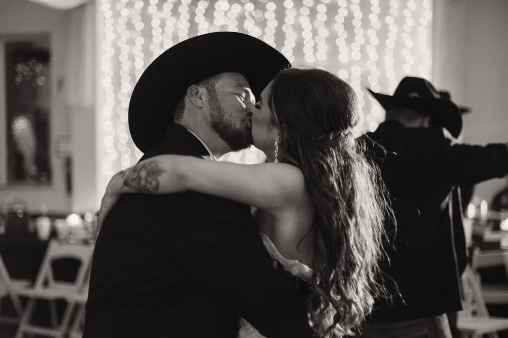 bride and groom share a kiss on the dance floor during their reception while mckinney wedding photographer captures the moment.